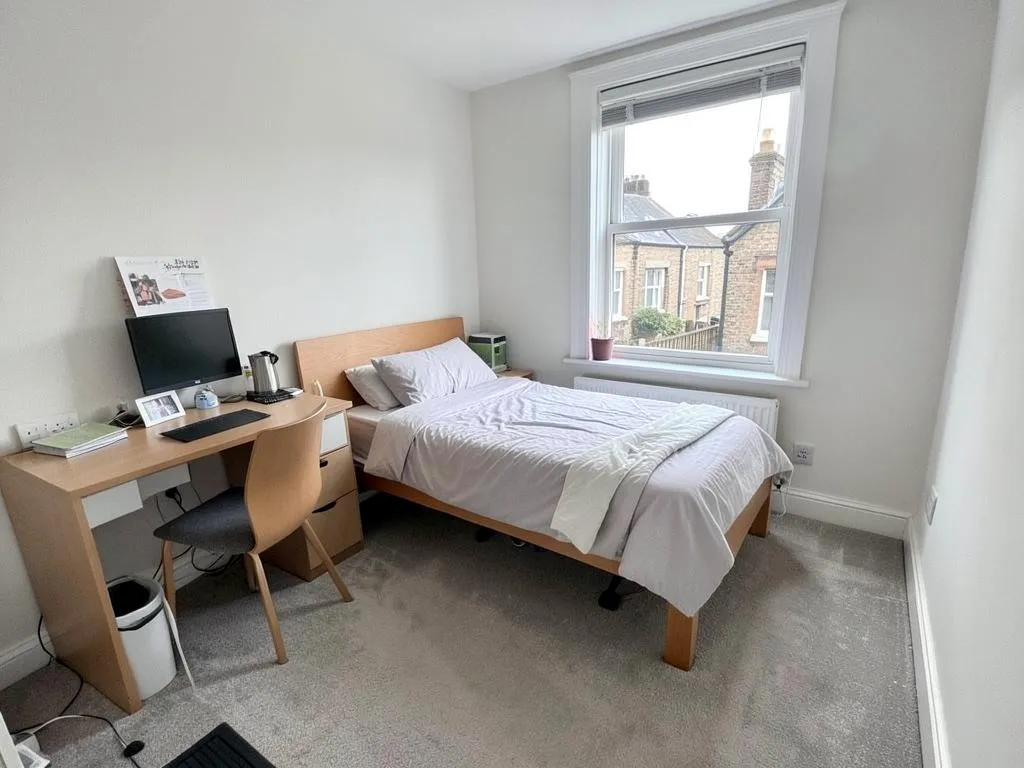 Cleaned single bedroom in a shared house with made bed, clear desk and vacuumed carpet
