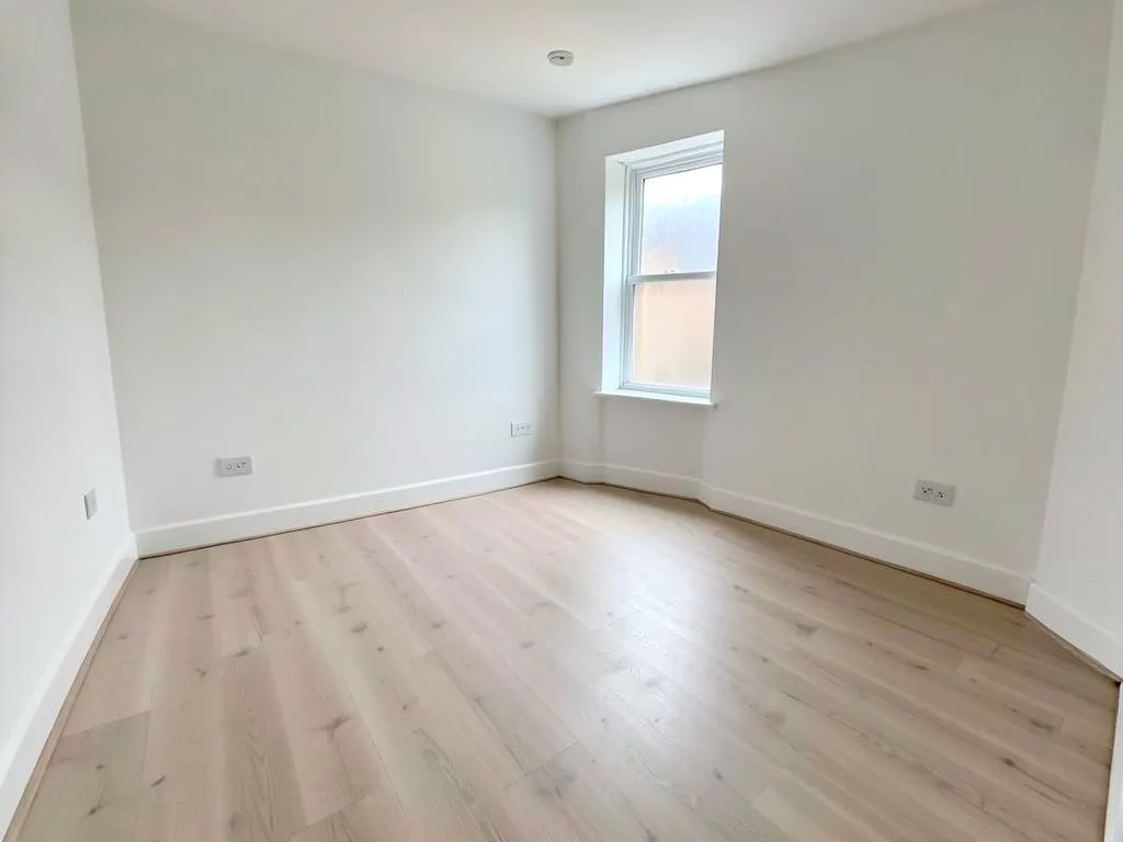 Empty rental room after a void clean with bare swept floor and spotless white walls