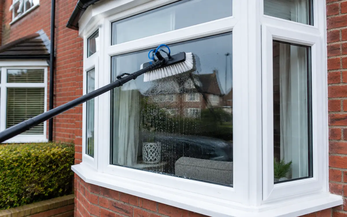 Water-fed pole brush cleaning exterior window glass, frames and sill